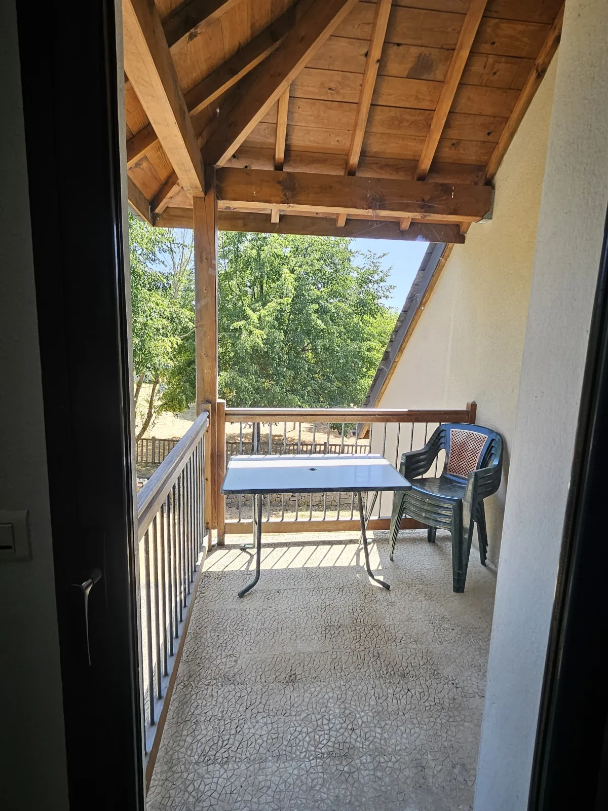 Balcon couvert avec table et chaises donnant sur la verdure, gîte La Pinatelle